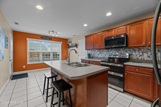 kitchen featuring decorative backsplash, sink, stainless steel appliances, and an island with sink