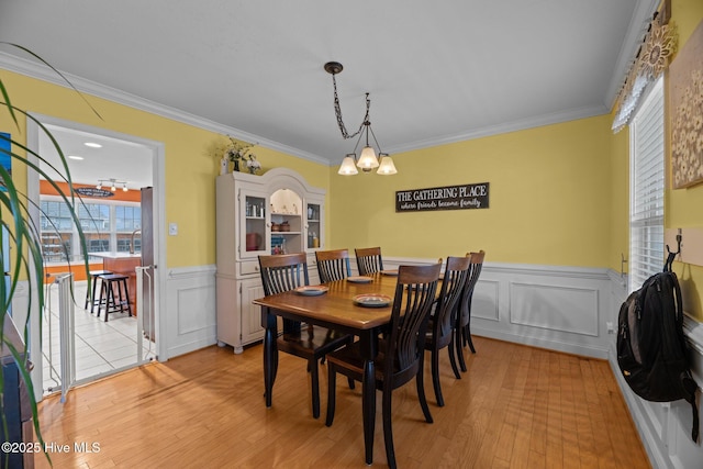 dining space featuring crown molding, light hardwood / wood-style flooring, and a notable chandelier