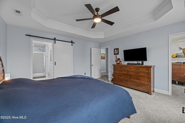 bedroom with ensuite bathroom, a barn door, and a raised ceiling