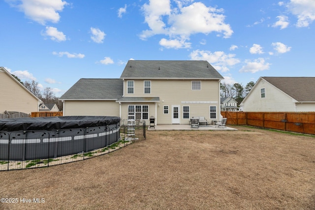 rear view of property featuring a yard, a patio, and a covered pool