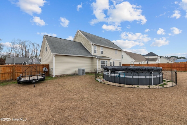 back of property with a yard, a covered pool, and cooling unit