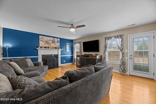 living room featuring ceiling fan, wood-type flooring, and a textured ceiling