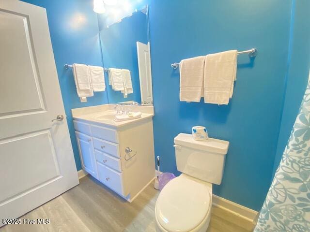 bathroom featuring wood-type flooring, vanity, and toilet