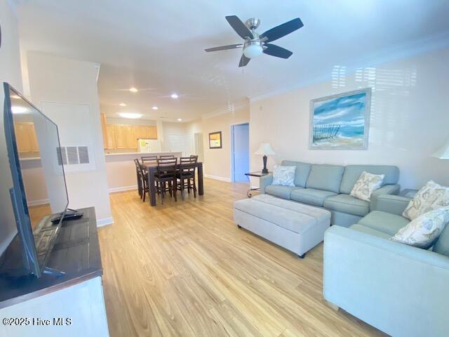 living room with light wood-type flooring, ceiling fan, and ornamental molding