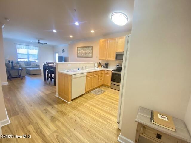 kitchen with kitchen peninsula, appliances with stainless steel finishes, ceiling fan, light brown cabinets, and light hardwood / wood-style floors