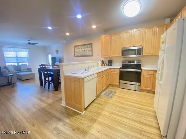 kitchen featuring sink, kitchen peninsula, light brown cabinetry, appliances with stainless steel finishes, and light wood-type flooring