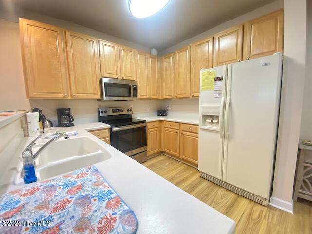 kitchen with sink, light hardwood / wood-style floors, light brown cabinets, and appliances with stainless steel finishes