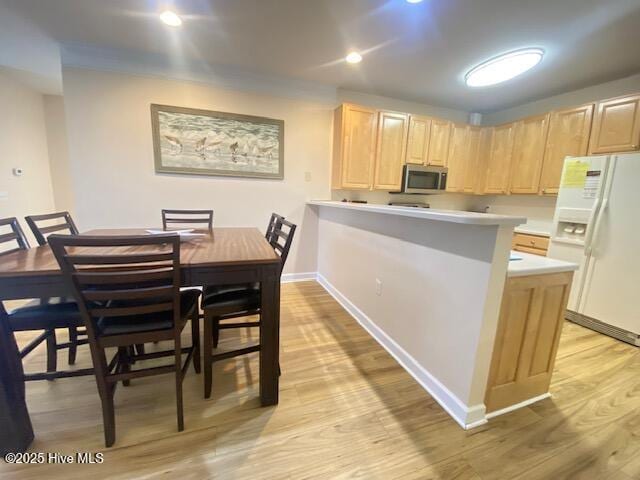 kitchen with light brown cabinets, light wood-type flooring, and white fridge with ice dispenser