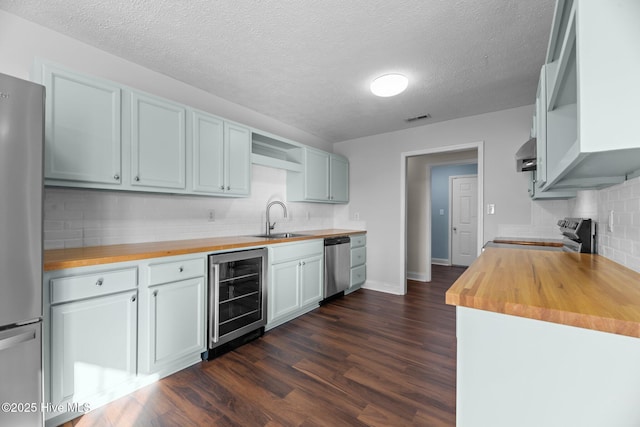 kitchen featuring wood counters, tasteful backsplash, stainless steel appliances, sink, and wine cooler