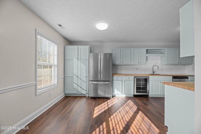 kitchen with backsplash, sink, appliances with stainless steel finishes, dark hardwood / wood-style flooring, and beverage cooler