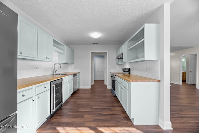 kitchen with wooden counters, appliances with stainless steel finishes, white cabinetry, and beverage cooler