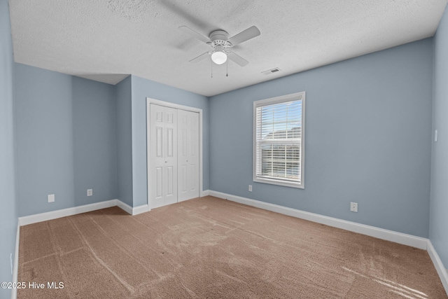 unfurnished bedroom featuring carpet, a textured ceiling, a closet, and ceiling fan