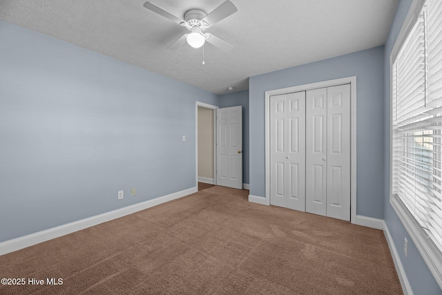 unfurnished bedroom featuring carpet, ceiling fan, multiple windows, and a closet