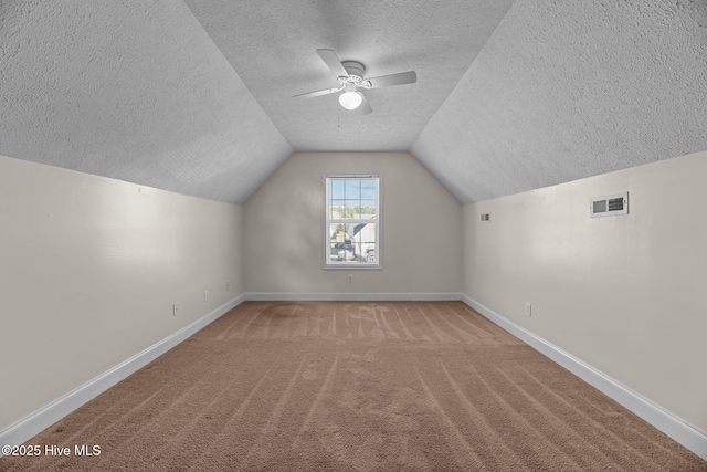 additional living space with a textured ceiling, light carpet, ceiling fan, and vaulted ceiling