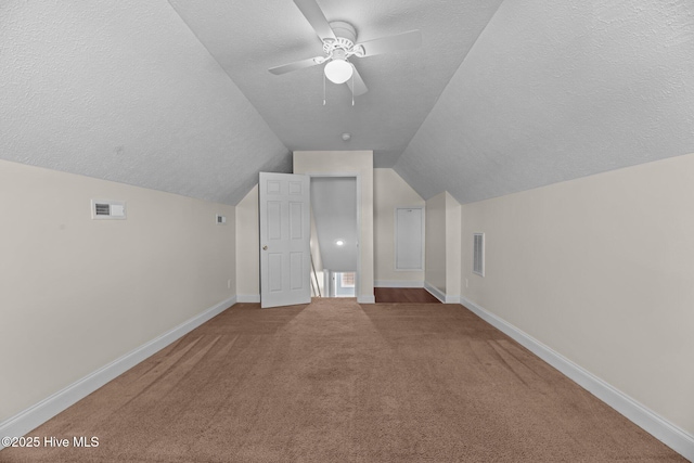 bonus room with lofted ceiling, ceiling fan, carpet floors, and a textured ceiling