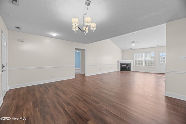 unfurnished living room with ceiling fan with notable chandelier, lofted ceiling, a textured ceiling, and dark wood-type flooring