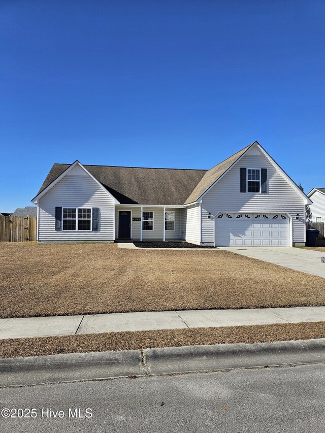 traditional-style house featuring a garage, driveway, a front lawn, and fence