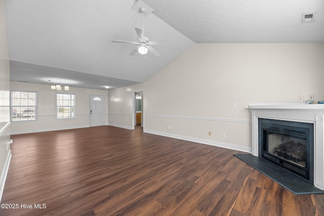 unfurnished living room with ceiling fan with notable chandelier, dark hardwood / wood-style flooring, and vaulted ceiling