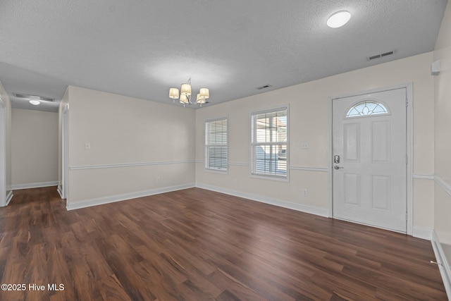 foyer entrance featuring a chandelier, a textured ceiling, and dark hardwood / wood-style floors