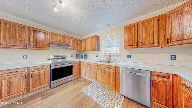 kitchen featuring appliances with stainless steel finishes, a textured ceiling, ornamental molding, and sink