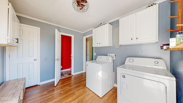 laundry area with cabinets, ornamental molding, light wood-type flooring, and washing machine and clothes dryer