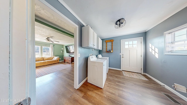 washroom with cabinets, independent washer and dryer, crown molding, and light hardwood / wood-style flooring