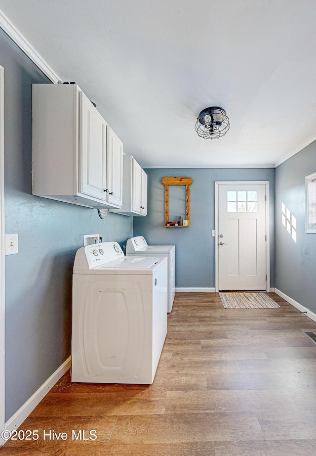 laundry area featuring cabinets, light hardwood / wood-style floors, and washer and clothes dryer