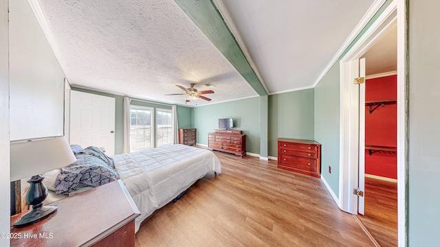 bedroom featuring ceiling fan, ornamental molding, a textured ceiling, and light hardwood / wood-style flooring