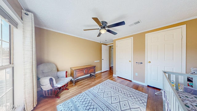 living area featuring wood-type flooring, a textured ceiling, ceiling fan, and crown molding