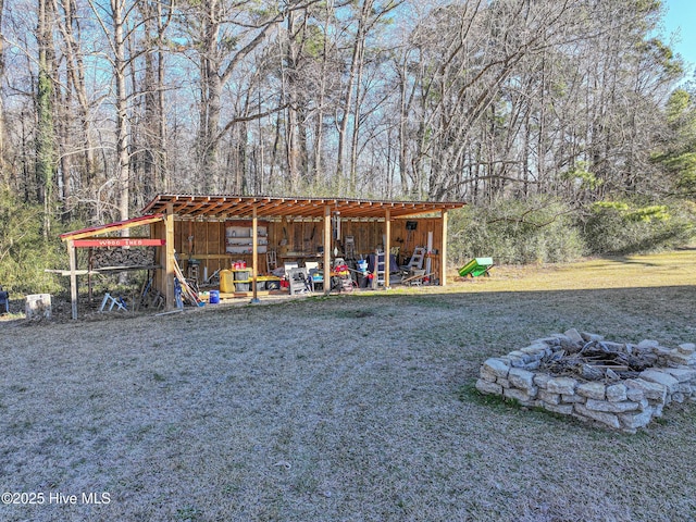 view of yard featuring an outdoor structure and an outdoor fire pit