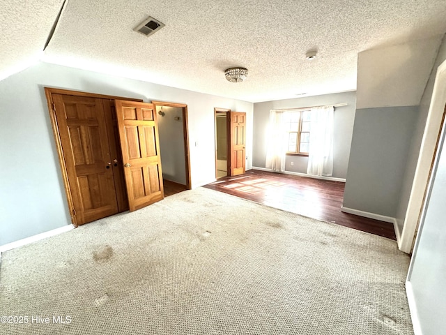 carpeted empty room with vaulted ceiling and a textured ceiling