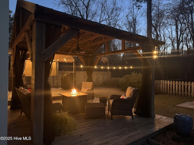 deck at dusk featuring a gazebo and an outdoor living space with a fire pit