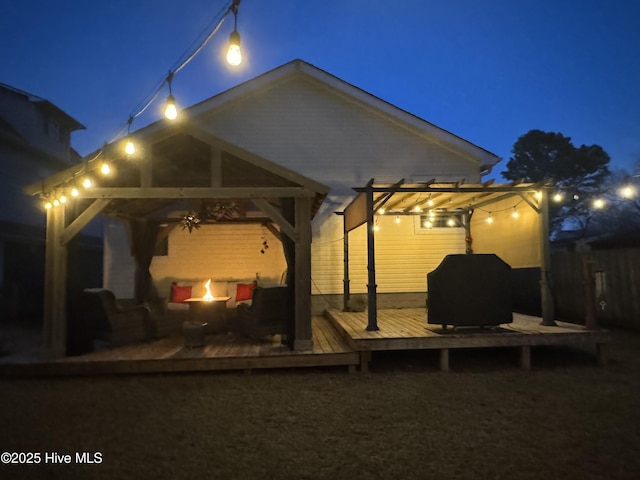 patio at night featuring a deck and a pergola