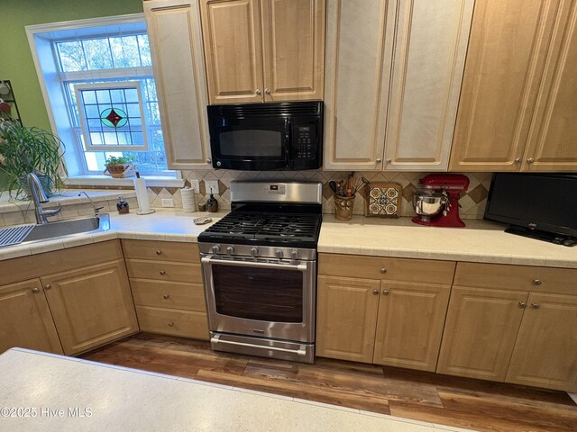 kitchen featuring dark wood-type flooring, light brown cabinetry, tasteful backsplash, stainless steel range with gas stovetop, and sink