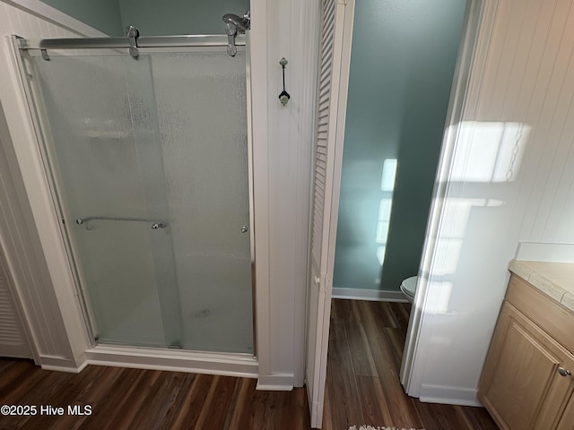 bathroom featuring walk in shower, hardwood / wood-style floors, vanity, and toilet