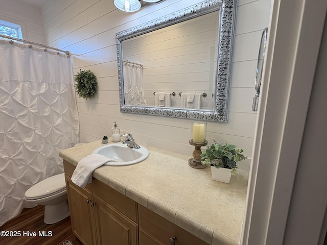 bathroom with toilet, walk in shower, vanity, wooden walls, and hardwood / wood-style flooring