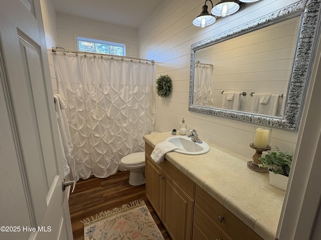 bathroom with toilet, vanity, and hardwood / wood-style floors