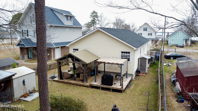 rear view of property featuring a deck, a yard, and a shed