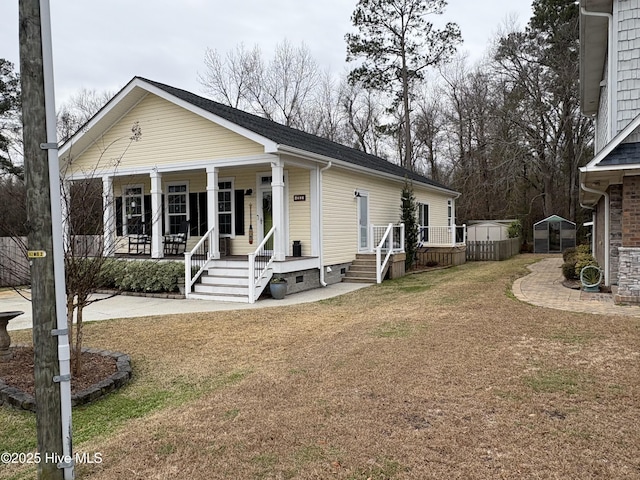 view of front facade featuring covered porch, a storage unit, and a front lawn