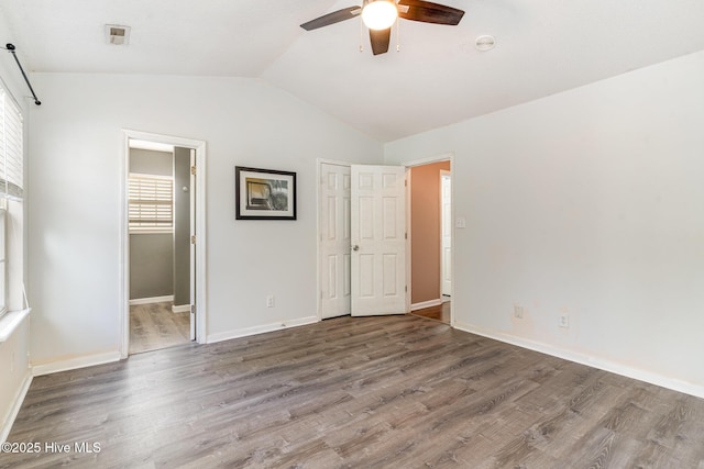 unfurnished bedroom with hardwood / wood-style floors, ceiling fan, ensuite bathroom, and vaulted ceiling