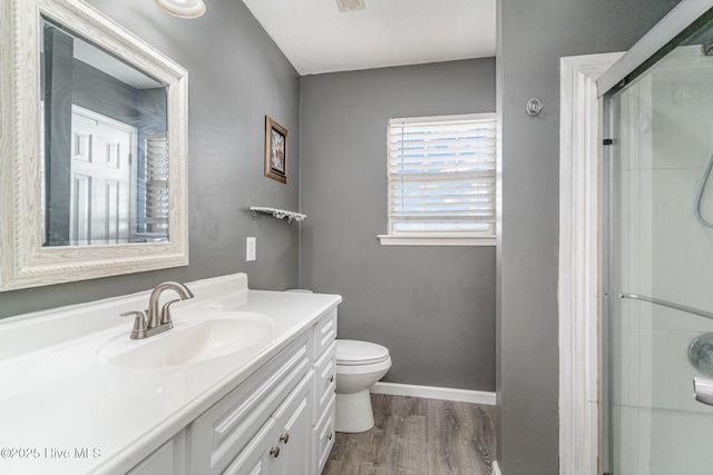 bathroom featuring hardwood / wood-style floors, vanity, toilet, and a shower with door