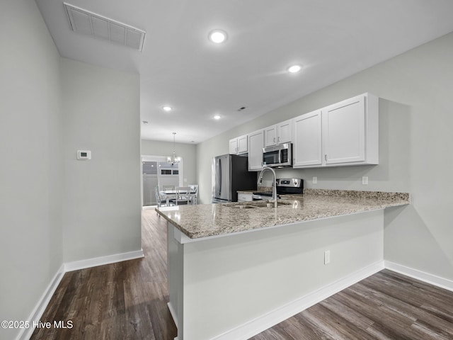 kitchen with sink, dark wood-type flooring, appliances with stainless steel finishes, white cabinetry, and kitchen peninsula