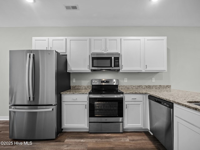 kitchen with white cabinetry, stainless steel appliances, dark hardwood / wood-style flooring, and light stone countertops