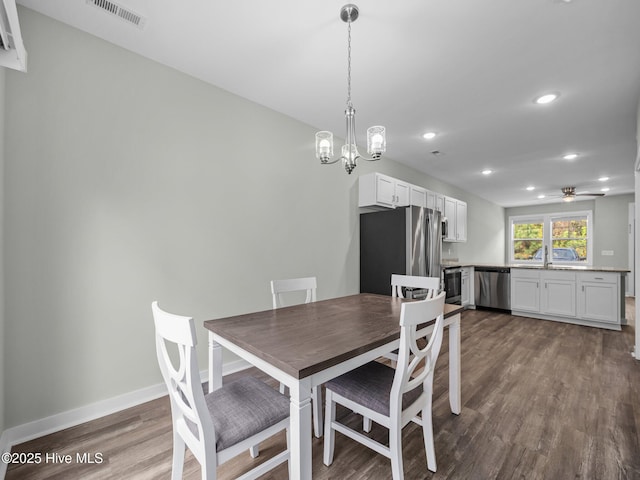 dining room with ceiling fan with notable chandelier, sink, and hardwood / wood-style floors