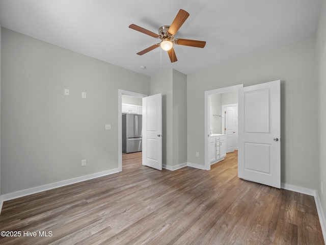 unfurnished bedroom featuring connected bathroom, stainless steel fridge, light hardwood / wood-style floors, and ceiling fan