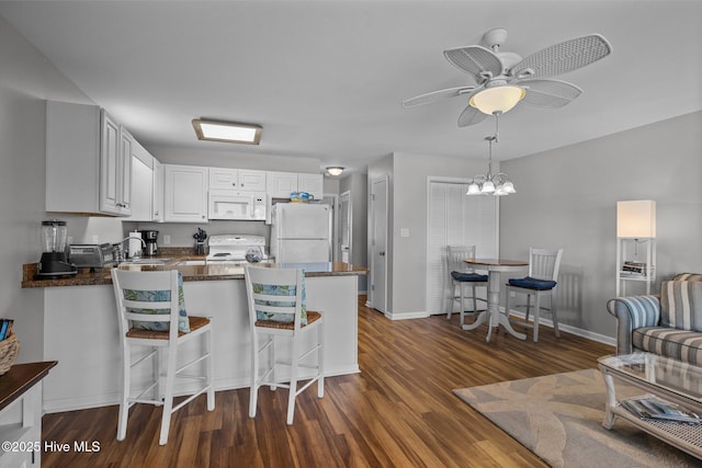 kitchen with kitchen peninsula, white cabinets, dark wood-type flooring, and white appliances