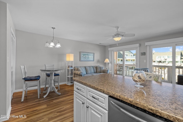 kitchen featuring dark hardwood / wood-style flooring, stainless steel dishwasher, ceiling fan with notable chandelier, pendant lighting, and white cabinets