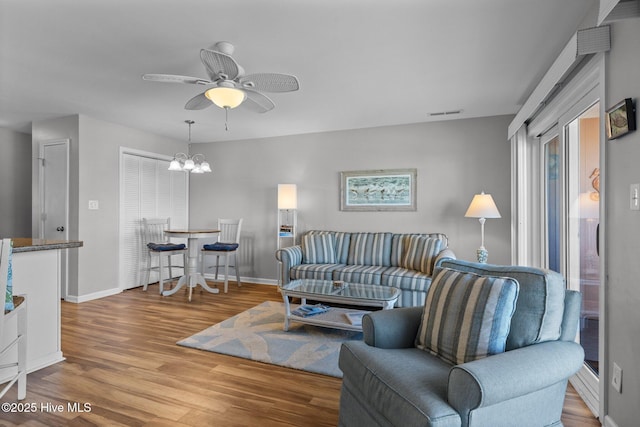 living room featuring ceiling fan with notable chandelier and hardwood / wood-style flooring