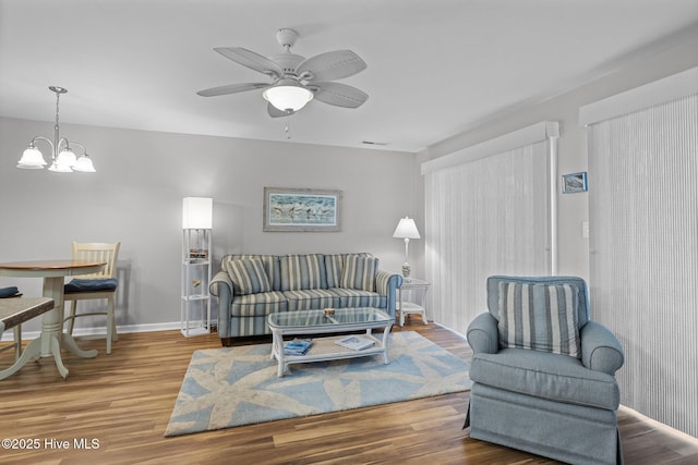 living room with ceiling fan with notable chandelier and hardwood / wood-style flooring