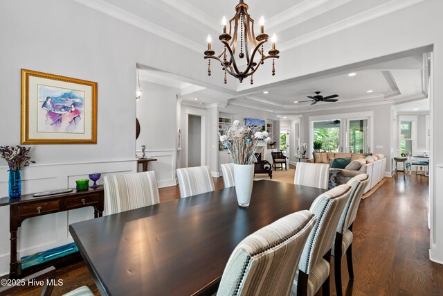 living room with dark wood-type flooring, a raised ceiling, ceiling fan, and crown molding